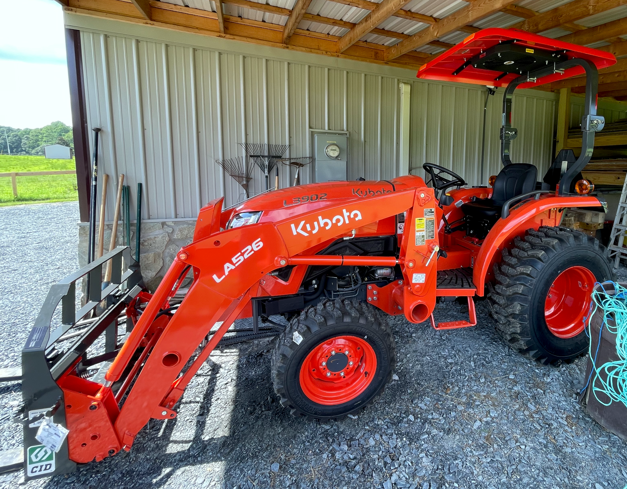An orange L3902 Kubota tractor with a front end loader with fork attachment