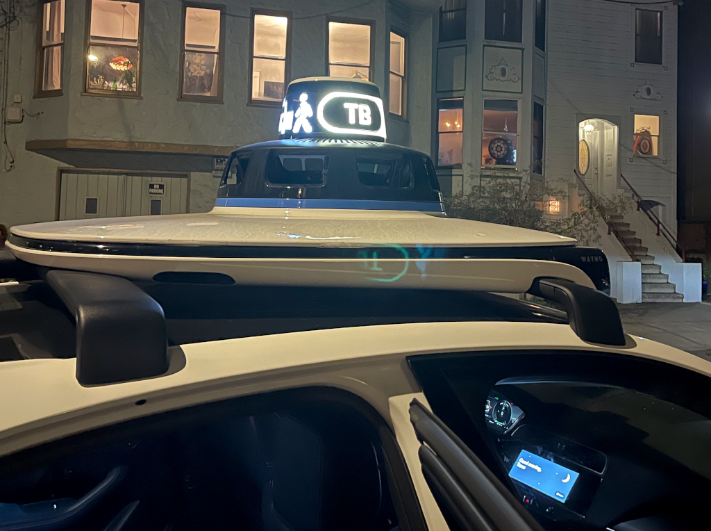 A Waymo displaying TB on the roof